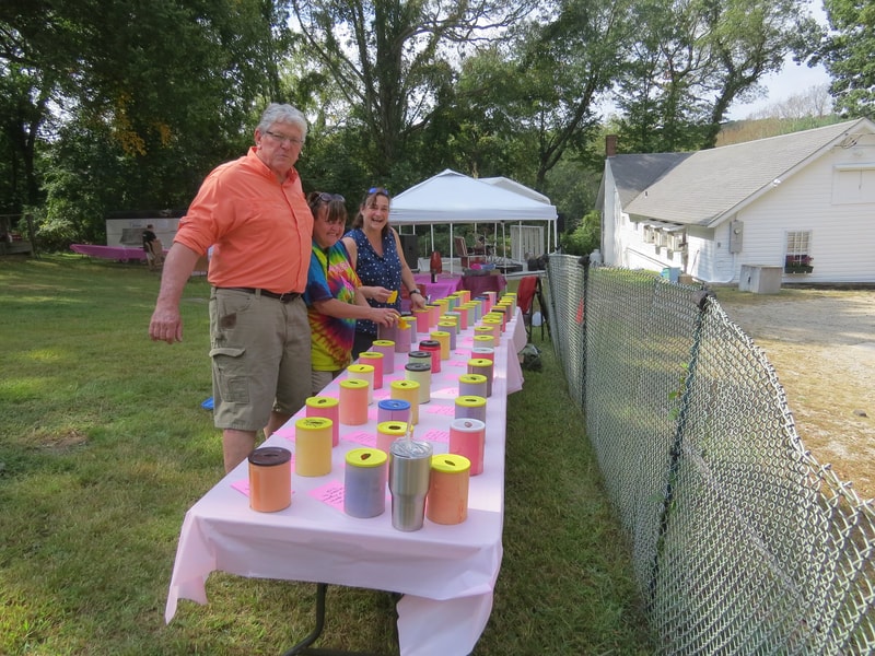 Volunteers with the colorful donation jar table at Boobstock