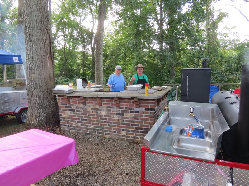 Two people at the brick BBQ grill station at Boobstock